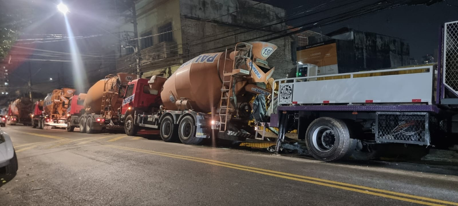 Caminhões betoneira posicionados para concretagem noturna