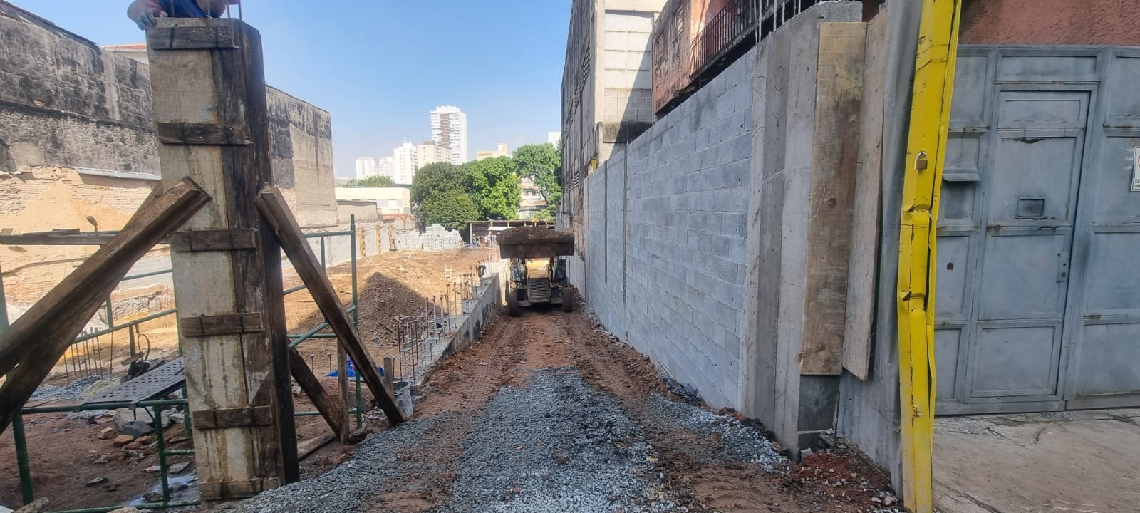 Acesso à obra com retroescavadeira e estrutura em execução